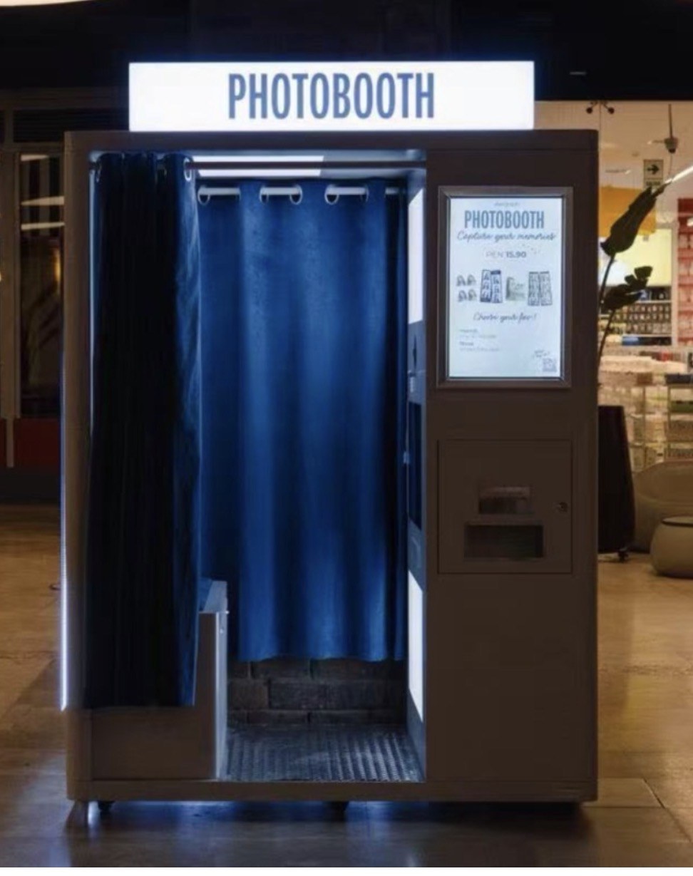 Enclosed photo booth with a lit Photobooth sign and a blue curtain