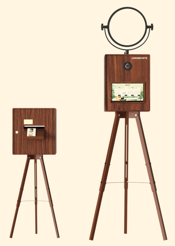 Wooden photo booth on a tripod with a ring light, beside its print stand